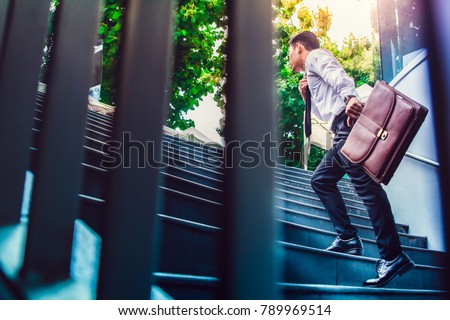 Young Asian businessman holding Brown leather bag working on staircase go office hurry work time with sunset top view and  instagram style filter photo vintage tone