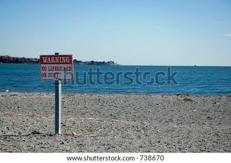 Sign warning that there is no lifeguard on duty at the beach.  Focus on Sign.