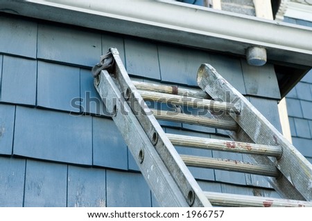 well-used extension ladder balanced against the back of a house, poised to allow access to the house gutters.
