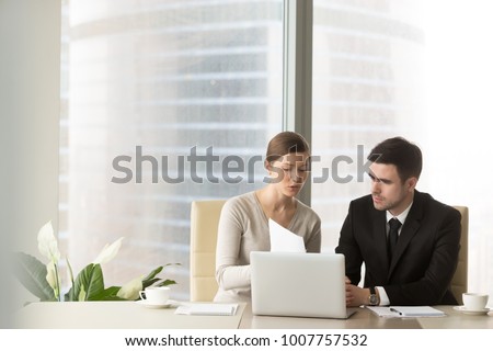 Millennial businesswoman discussing company indicators with male business partner at meeting in office. Female financial consultant, credit expert explaining terms of contract to client or investor
