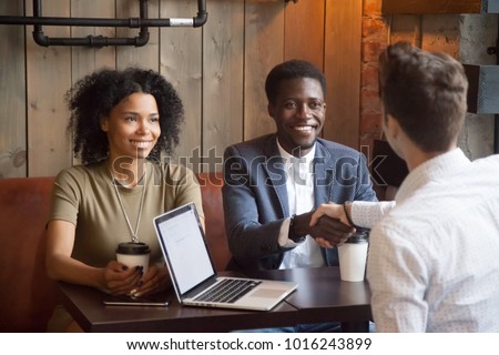 Smiling african american couple shaking hands to mortgage insurance broker, financial advisor or agent at cafe meeting, happy black woman and man handshaking white lawyer or consultant making deal