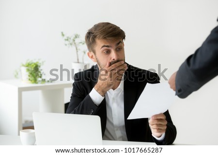 Surprised confused caucasian employee receiving dismissal notice, letter or document with unexpected news from african boss, worried shocked office worker getting fired in written message at work