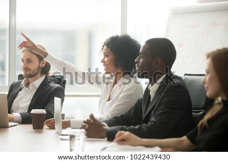 African woman raising hand to ask question at team training, curious black employee or conference seminar participant vote as volunteer at group office meeting with multiracial diverse businesspeople