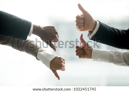 Hands of diverse business people showing thumbs up and down, like versus dislike gesture, positive negative feedback, yes and no opposition voting, confrontation disagreement at negotiations concept