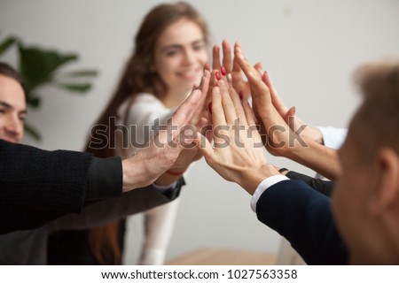 Motivated successful business team giving high five, happy young students employees group join hands with senior teacher mentor, team building unity concept, help support in teamwork, close up view