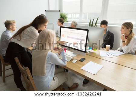 Young manager teaching senior worker explains planning work in office, corporate teacher helps older employee with application, aged woman using calendar on group computer training, mentoring concept