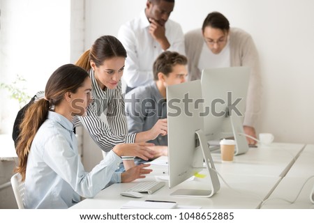 Executive mentor explaining intern or new employee online task pointing at computer screen, female boss supervisor teaching young girl to use corporate software or helping with difficult assignment