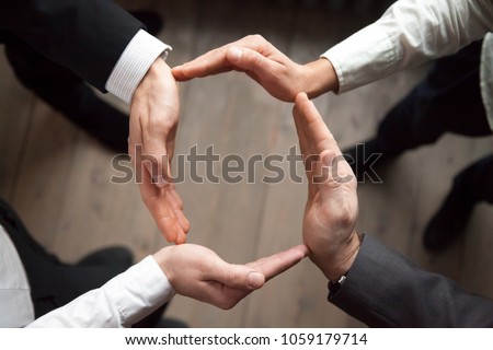 Business team people join hands forming circle, business protection, unity in care and support, shared corporate responsibility, help in teamwork, synergy trust safety concept, close up top view
