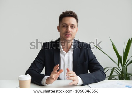 Confident CEO looking at camera talking about company strategy and business plan, explaining corporate success. Young entrepreneur shooting for online webinar, recording video blog. Headshot portrait