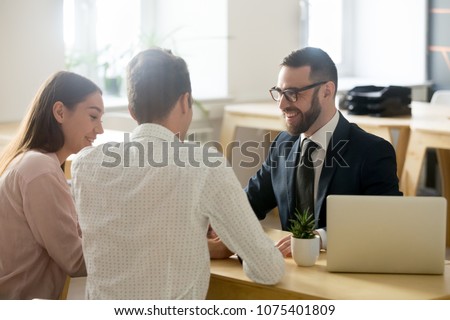 Friendly lawyer or financial advisor in suit consulting young couple, smiling investment broker or bank worker making loan offer, giving legal advice, selling insurance or real estate to customers