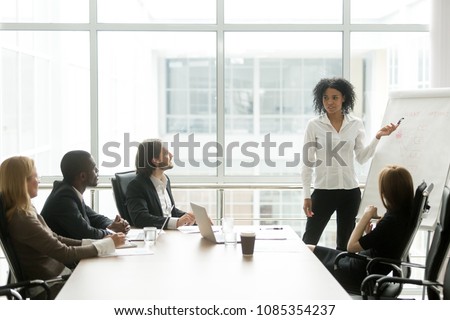 African american businesswoman giving presentation to executive team in meeting room, black business coach or employee working with flipchart reporting about work result, explaining new project idea