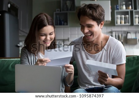 Happy young couple excited by reading good news in paper letter about refund tax money, millennial man and woman glad to receive special offer about cheap deal, test results or invitation by mail