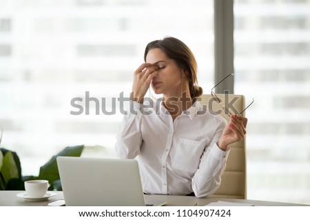 Fatigued businesswoman taking off glasses tired of computer work, exhausted employee suffering from blurry vision symptoms after long laptop use, overworked woman feels eye strain tension problem