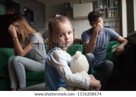 Frustrated little girl upset tired of parents fight looking at camera, portrait of sad preschool kid daughter suffers from family mom and dad arguments or lack of attention, child and divorce concept