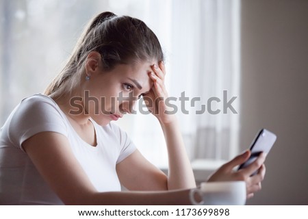 Angry young woman looking at smartphone frustrated by no signal or scam message, mad female disappointed by bad news reading on phone, upset girl get negative or rejection response on mobile