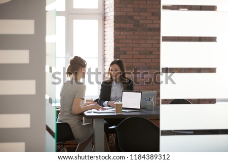Businesswomen discussing project results and planning work in meeting room, female marketing or sales executives talking in office, serious women colleagues sharing ideas about new corporate strategy