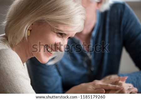 Happy middle aged senior woman with beautiful face laughing flirting with beloved older man, smiling loving wife enjoying humor talk with elderly husband, mature family couple having fun on date