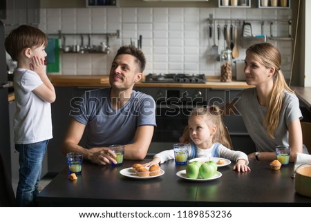 Little boy telling story, poems standing on chair at breakfast, mother, father, daughter listening to son, brother, happy family dine, spending time together