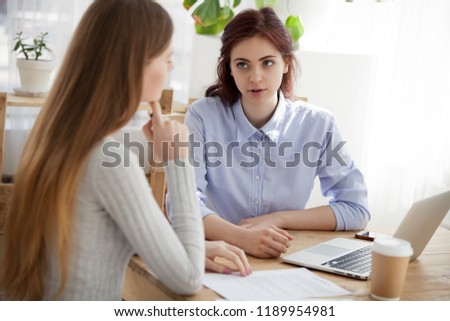 Caucasian millennial women sitting at the desk. Attractive advisor interviewing new candidate. Confident girls colleague coworking together at business meeting or client at real estate agency office