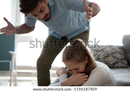 Unhappy crying frightened woman and aggressive man quarrelling at home. Angry husband emotionally arguing screaming shouting to scared wife psychological emotional abuse and domestic violence concept