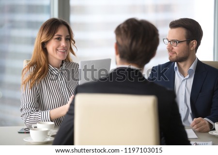Young broker businesswoman talking to business partners. Woman consulting, giving instructions, explaining terms of contract. Man in glasses looking colleague and listening.