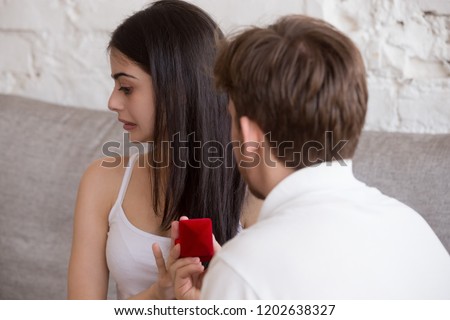 Loving man holding red box with marriage engagement ring doing proposal to young woman rejecting offer, girl with disgust on her face saying no, not taking ring, refuse marry boyfriend, breakup