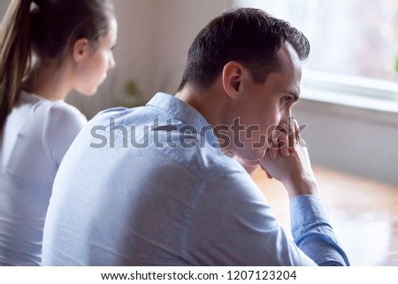 Spouses after quarrel sitting together at home thinking about relations and grievances. Couple not talk look at each other after verbal fight focus on man close up rear view. Break up divorce concept