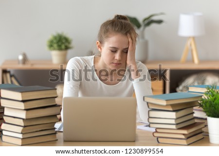 Tired girl sitting at work desk at home studying at laptop with books around, exhausted female fall asleep annoyed of learning, bothered student feel fatigue preparing for exam among course handbooks