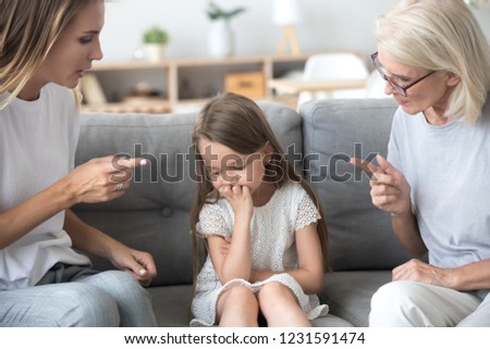 Angry mother and grandmother scolding lecturing upset kid girl together, strict young mom and old grandma talking to child reprimanding  demanding discipline, three generations upbringing concept