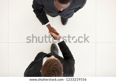 Two diverse businessmen shaking hands in office, black and white partners greeting with handshake as respect concept, collaboration deal, support, business acquaintance, first impression, top view