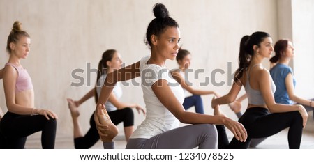 Multinational diverse young attractive sporty girls headed by mixed race coach, practising together yoga doing One Legged King Pigeon pose stretches body. Horizontal photography banner for website