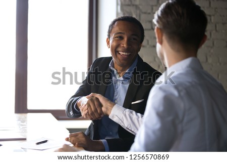 Happy satisfied black client shaking hands thanking manager for good financial deal, african american businessman handshaking partner after successful business negotiations, hiring, buying services