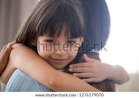 Cute little child girl embracing loving mother, happy kid hugging mom holding tight cuddling, sincere affectionate relationships between mum and daughter, moms love support care or adoption concept