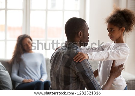 African dad talking to daughter supporting or explaining little mixed race girl during friendly conversation at home, black father speaking to child having good trustful relationships with kid
