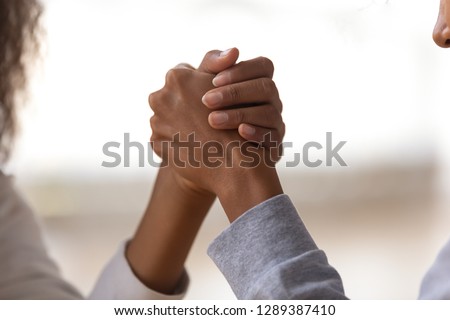 Close up of mom and daughter holding hands showing unity, support and understanding, African American female friends play funny wrestle game, mother or nanny and child unity concept