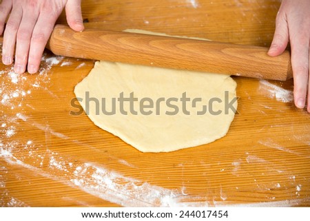 Close up homemade cooking, female hands roll out pastry with rolling-pin on wooden table