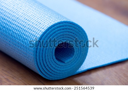 Close up of rolled blue yoga, pilates mat on the floor. Healthy life, keep fit concepts