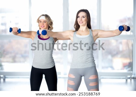 Active, healthy lifestyle, hobby, recreation, wellbeing, weight loss concepts. Team of two athletic girls having intensive aerobics and muscle training with dumbbells in class