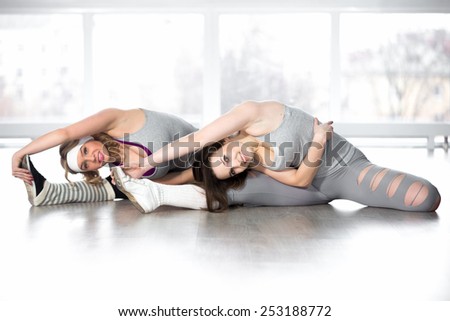 Active, healthy lifestyle, hobby, recreation, wellbeing, weight loss concepts. Two dancer girls warming up with stretching exercises for flexibility during class in white sports hall