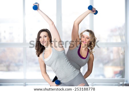 Active, healthy lifestyle, hobby, recreation, wellbeing, weight loss concepts. Two athletic girls doing aerobics and muscle training with dumbbells in class