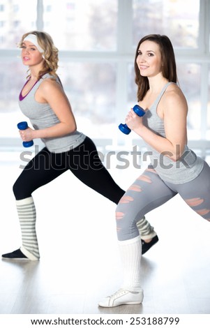 Active, healthy lifestyle, hobby, recreation, wellbeing, weight loss concepts. Two athletic girls doing fitness aerobic exercises with dumbbells in class