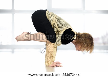 Sporty dancer woman in class working out, doing aerobics training, practicing handstand, doing yoga crane pose bakasana