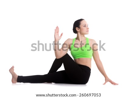 Beautiful athletic girl practicing seated spinal twist, Half lord of the fishes pose, Ardha Matsyendrasana, yoga for back and hips