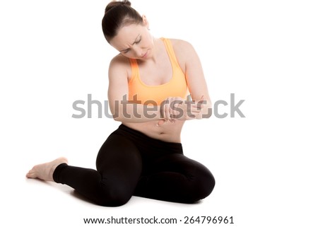 Young athlete girl in sportswear frowning from pain touching aching wrist, injured after sport practice, feeling pain in ligament, sprained forearm