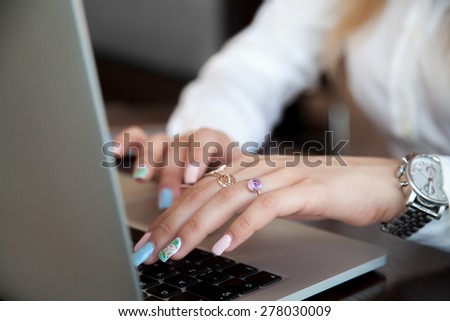 Modern office girl hands on laptop using touch pad and keyboard with rings on fingers and colorful manicure, close up