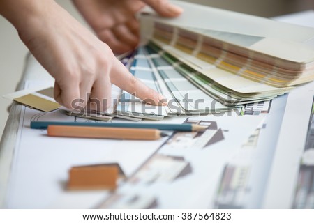 Creative people workplace. Close-up view of hands of young designer woman working with color palette at office desk. Attractive model choosing color samples for design project. Interior shot