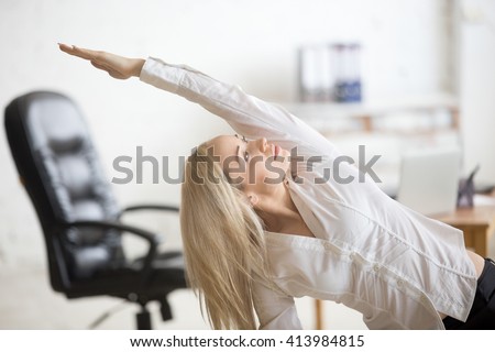 Business and healthy lifestyle concept. Portrait of young office woman doing fitness exercise at workplace. Happy beautiful business lady doing side bending posture on her break time