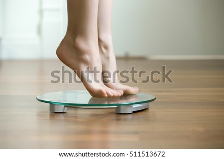 Female on tiptoes standing on glass floor weight scales, closeup