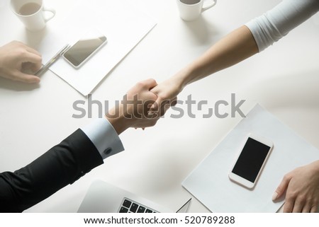 Top view of a strong handshake between man and woman, both sides viewpoints and interests have been considered. Effective negotiation with client. Business concept photo. Horizontal