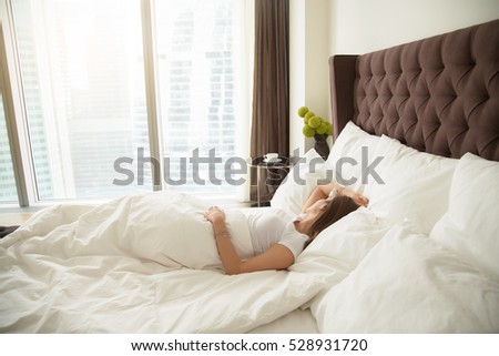 Young woman sleeping comfortably, quality bed linen and bedding, staples quilts and pillows, drank too much the night before, too lazy to shower, having her periods, single woman, overslept